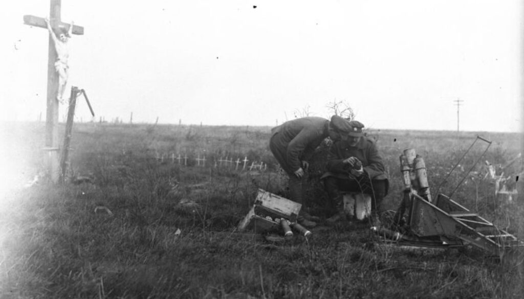 249_Canadians looking at German trench mortar ammunition. Crucifix in background. October, 1918.
